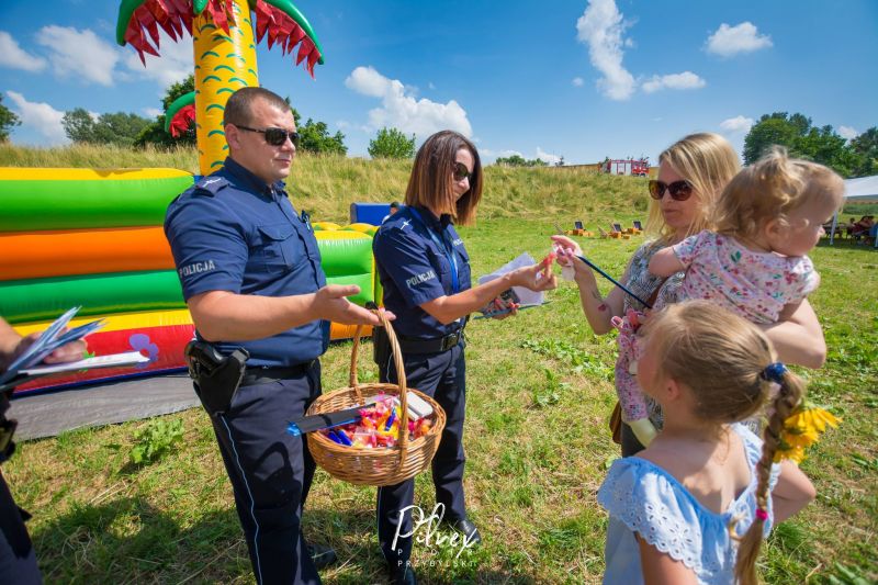 funkcjonariusze policji rozdający dzieciom cukierki_piknik rodzinny w Bienkówce Bezpieczne wakacje na wsi_4 lipca 2021 r